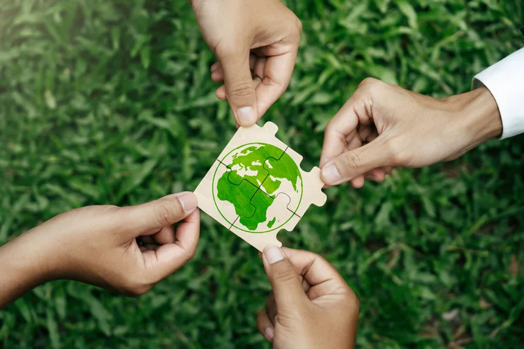 hands holding puzzle pieces together that form the earth