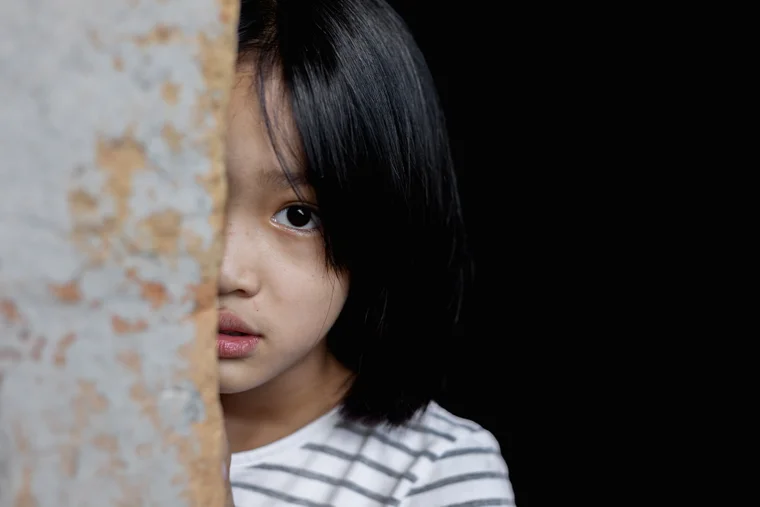 young child peeking from behind a wall